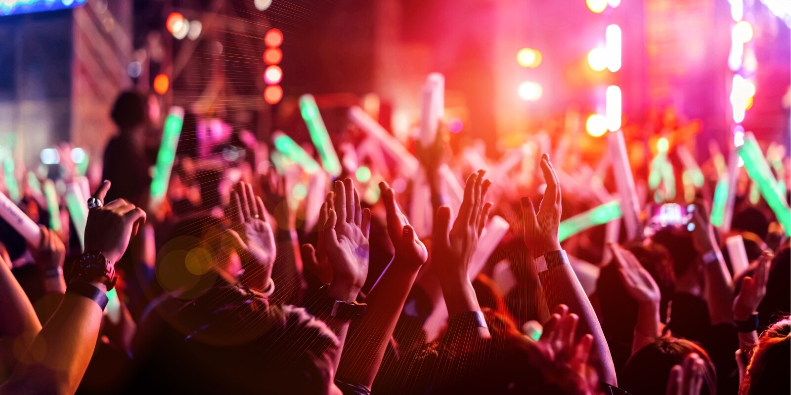 Crowd of people at a live concert with pink and orange lights