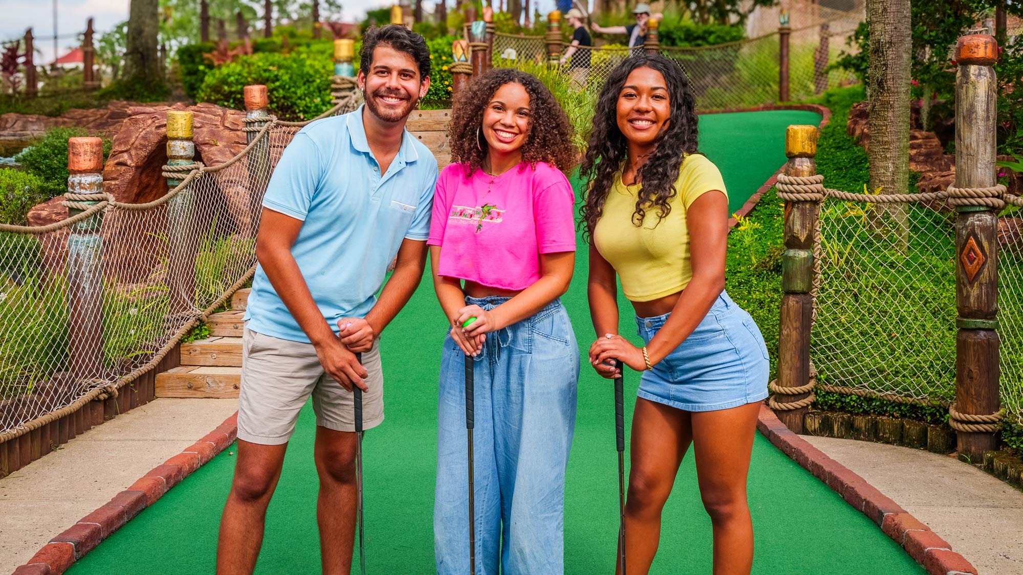 a man and two women playing mini golf