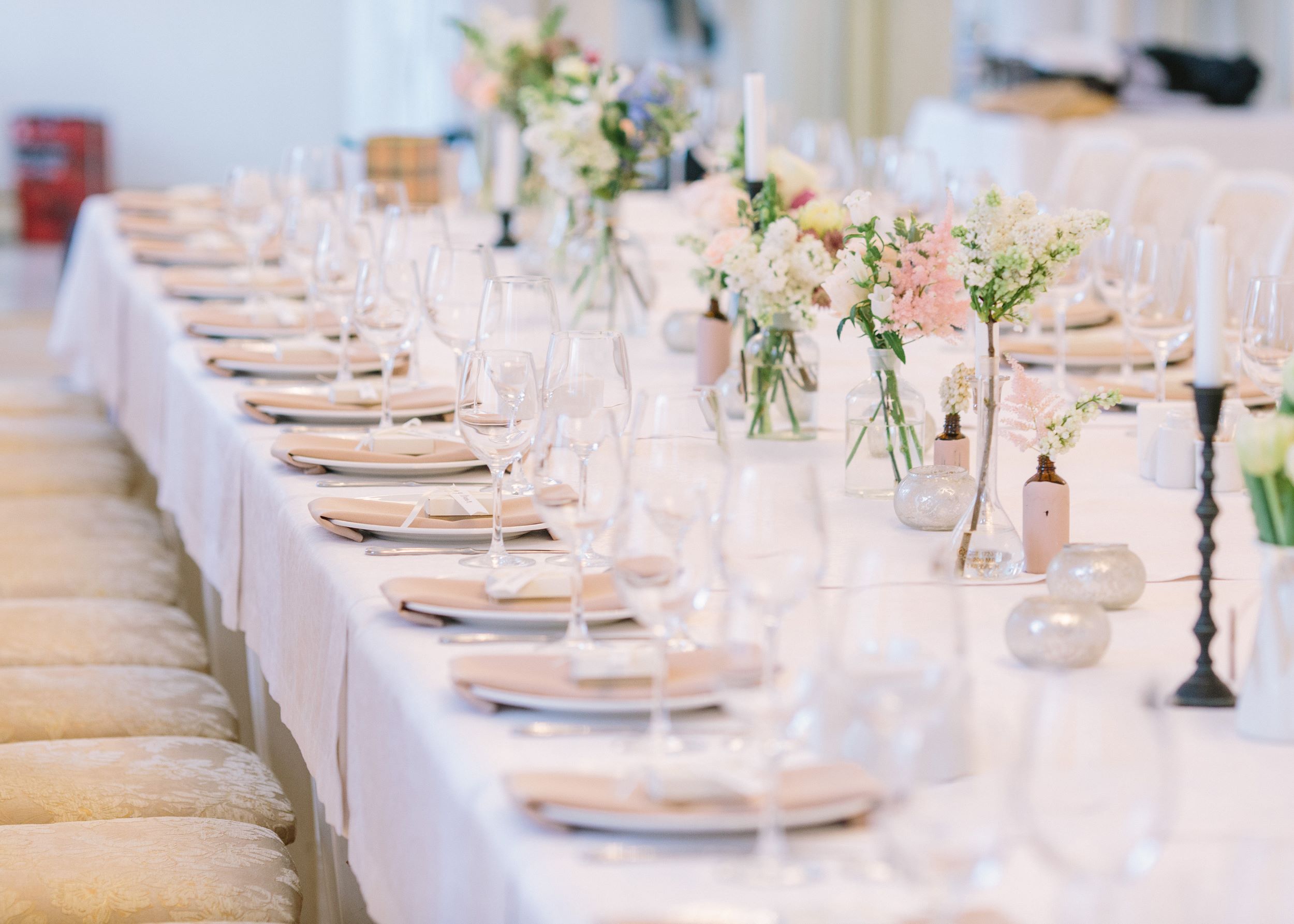 wedding table with 12 place settings, vases with pink flowers, candle sticks